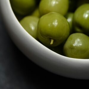 a white bowl filled with green olives on a table